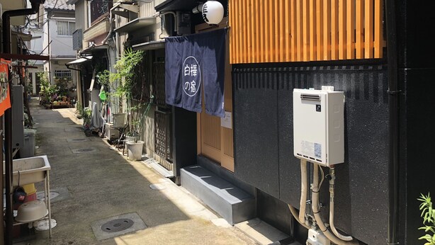 A narrow alley with buildings on either side, a wooden fence, and a sign with Japanese characters. - Shirakabanoyado-keigetsu (Osaka)
