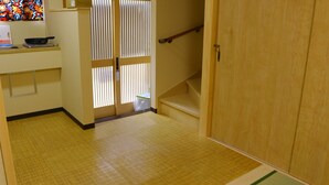 A hallway with a wooden floor, a staircase, and a door with vertical blinds. - Shirakabanoyado-keigetsu (Osaka)