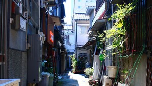 A narrow alleyway between buildings with potted plants and outdoor furniture. - Shirakabanoyado-keigetsu (Osaka)