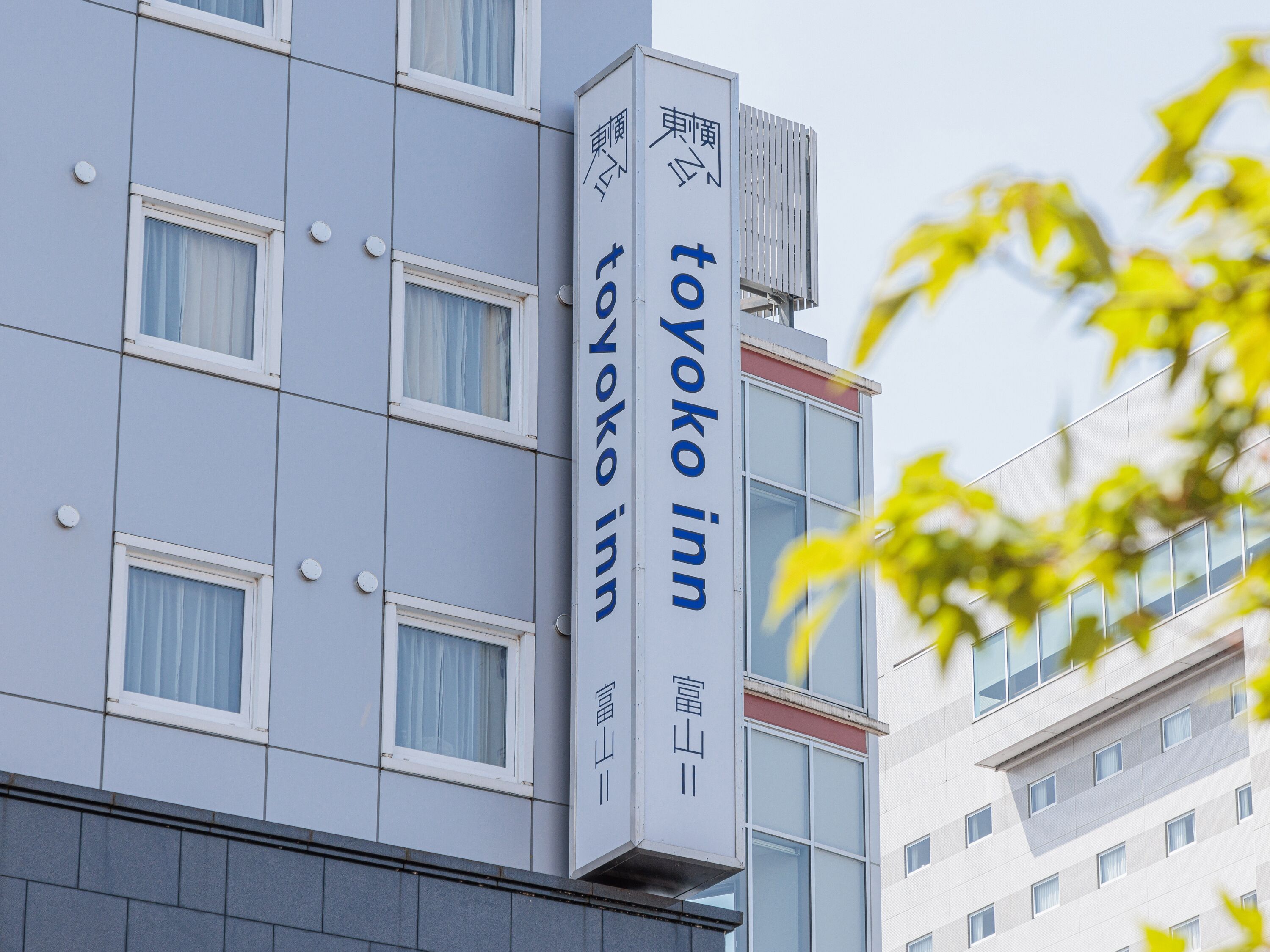 A building with a sign for Toyako Inn, featuring a modern architectural style with multiple windows and a clear sky in the background.