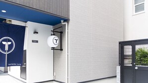 A building entrance with a blue awning displaying a logo, a sign reading "TATERU bnb," and a black gate. - Trip Pod Sumiyoshi A (Fukuoka)