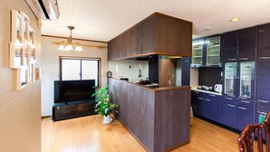 A modern kitchen with a central island, built-in appliances, and a dining area with a wooden table and chairs. - Shirakabanoyado-Minato (Osaka)