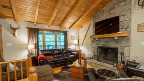 A cozy living room with a stone fireplace, leather furniture, and a mounted deer head. - Cabin By Blue Ridge Parkway (Blowing Rock)