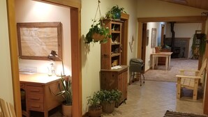 Una habitación amplia con un escritorio de madera, una silla, una estantería y una planta colgante.