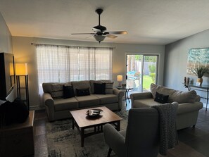Relax in this inviting living room with a sofa, armchair, and coffee table, perfect for unwinding with a good book or enjoying a meal on the adjacent patio.