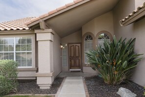 Stucco-clad building with a central entrance, flanked by windows and a decorative archway.