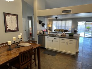 Enjoy meals in a spacious kitchen with a dining area, featuring a wooden dining table, kitchen island, and ample storage.