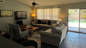 Ein Wohnzimmer mit einer Couch, Couchtisch, Fernseher und Deckenventilator.