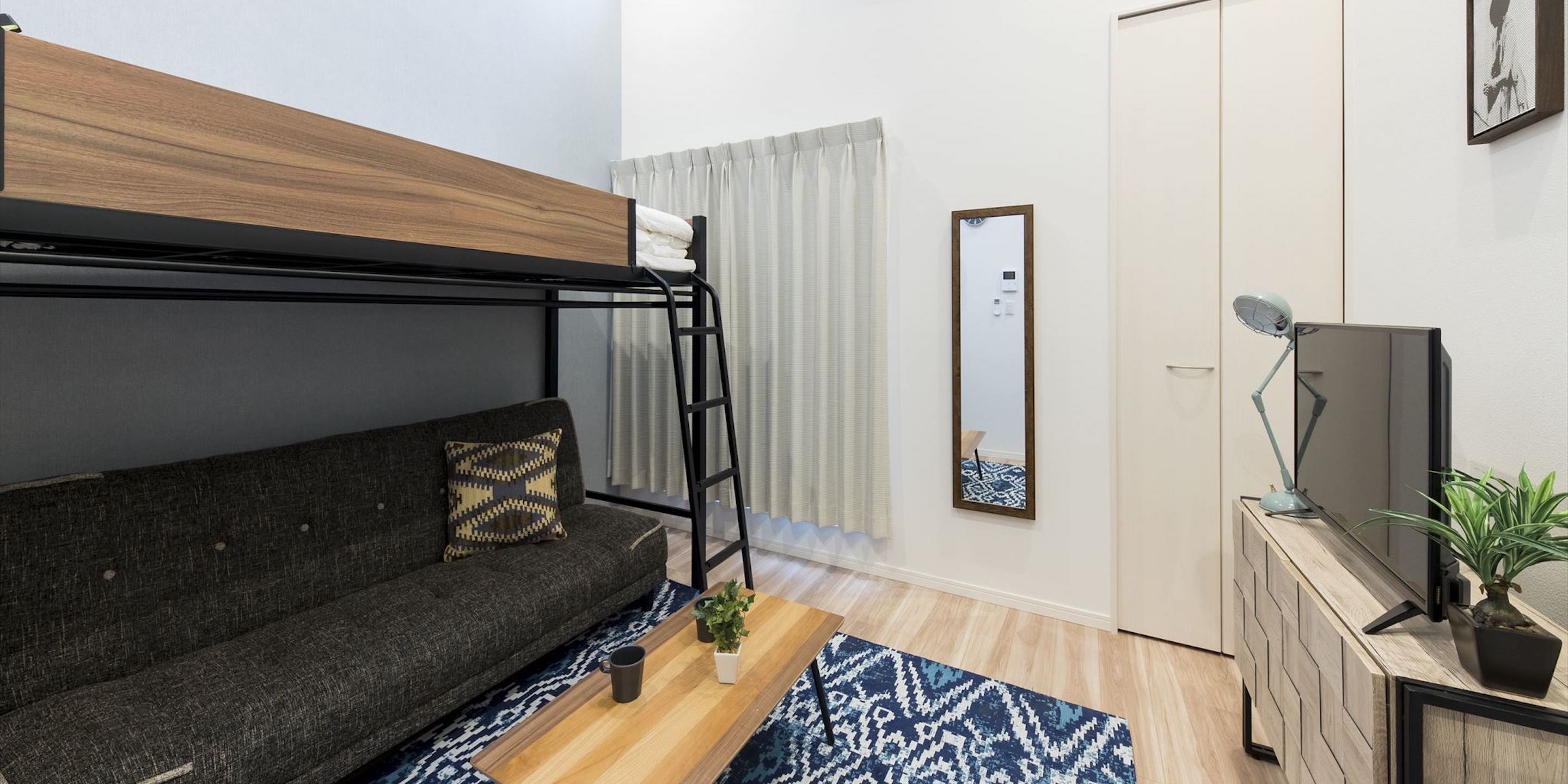 Une chambre moderne équipée d’un lit superposé, d’un canapé, d’une télévision, d’un bureau et d’un miroir.