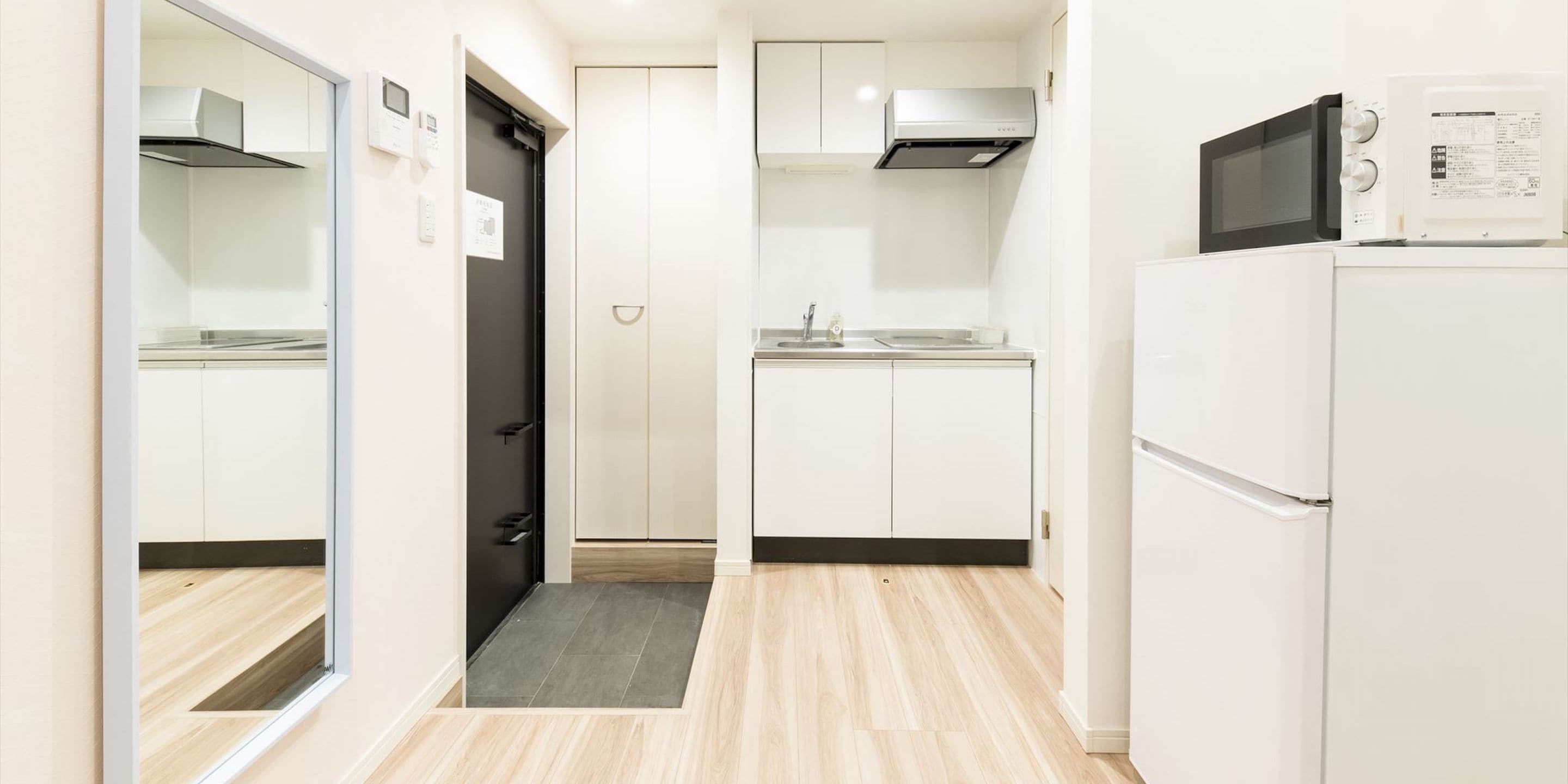 A modern kitchen with white cabinets, a black microwave, and a refrigerator.