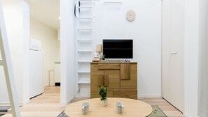 A modern kitchen with a built-in TV, wooden cabinets, and a small dining area with two chairs and a table. - Trip Pod Sumiyoshi C (Fukuoka)