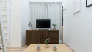 A modern living room with a wooden TV stand, a flat-screen TV, a small potted plant, and two mugs on a wooden table. - Trip Pod Sumiyoshi C (Fukuoka)