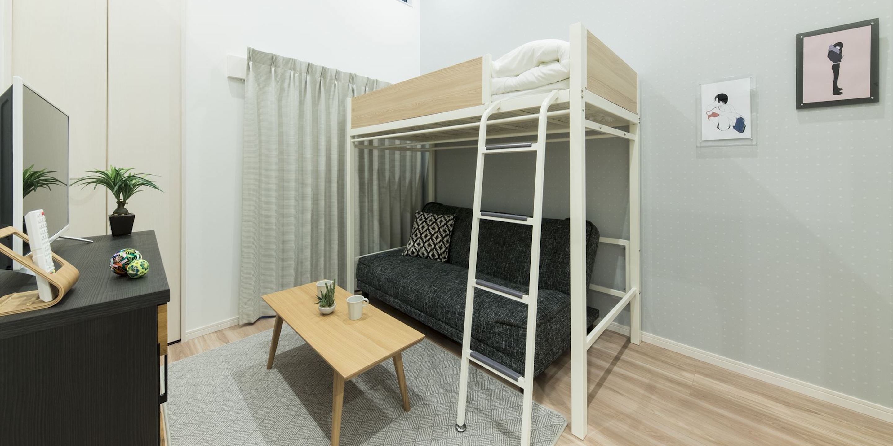 A bunk bed room with a desk, a small table, and two potted plants.