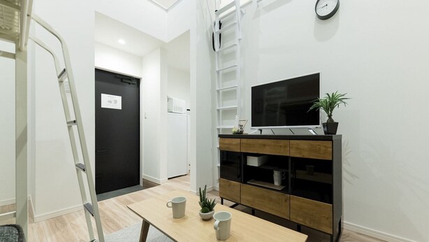 A modern living room with a TV, wooden cabinet, and a small table with cups and a plant. - Trip Pod Sumiyoshi C (Fukuoka)