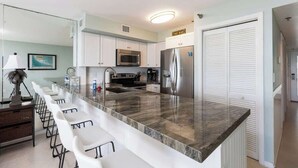A modern kitchen with a marble countertop, stainless steel appliances, and a bar area. - Sunrise Suite with Unobstructed Ocean Views (Tavernier)