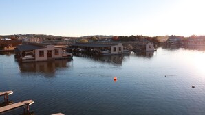 A calm waterfront area with floating structures, likely used for dining or lodging, surrounded by calm water and distant buildings. - Adorable waterfront condo, private docks, and bring the dog! (Horseshoe Bay)