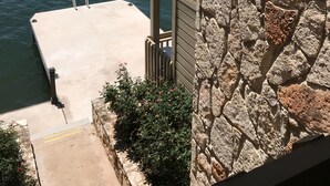 A stone building with a dock extending into a body of water, surrounded by greenery. - Adorable waterfront condo, private docks, and bring the dog! (Horseshoe Bay)
