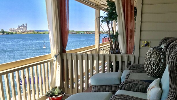 A covered outdoor seating area with wicker furniture and a view of the water. - Adorable waterfront condo, private docks, and bring the dog! (Horseshoe Bay)