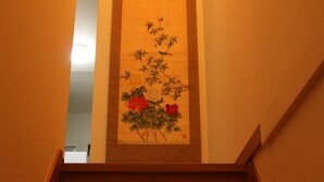 A wooden staircase leading to a room with a framed floral artwork on the wall. - Shirakabanoyado-sakuragawa (Osaka)