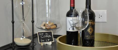 A wine display with bottles and a glass, a cork holder, and a sign.
