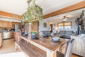 Eine geräumige Küche mit Holzschränken, einem Esstisch für vier Personen und einem gemütlichen Wohnbereich mit einer Couch und einem Kamin.