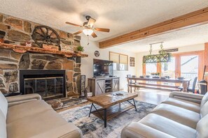 A living room with a stone fireplace, leather sofas, a wooden coffee table, and a television. - DEER HAVEN | MOUNTAIN VIEW | HOT TUB | VINEYARDS (Cleveland)