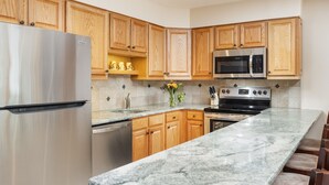 A modern kitchen with wooden cabinets, stainless steel appliances, and a granite countertop. - Montaneros 314 - 1 Bedroom Platinum (Vail)