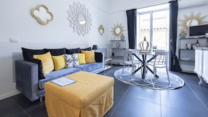 A modern living room with a sofa, ottoman, and dining table.