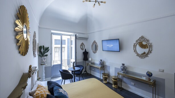 A bedroom with a bed, a desk, a chair, a television, and decorative mirrors.