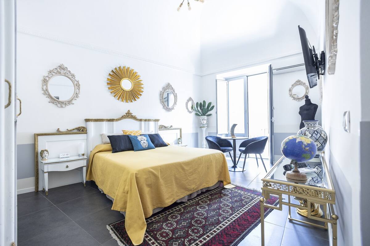 Une chambre à coucher avec un lit, des tables de chevet, un globe terrestre et un miroir.