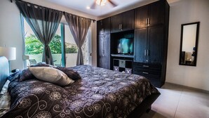 A bedroom with a large bed, dark wooden wardrobe, and a television. - Spectacular two level penthouse 850' to the beach and 1.5 blocks to 5th Ave. (Playa Del Carmen)