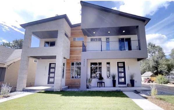 Two-story residential building with balconies and a well-manicured lawn.