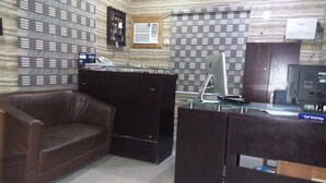 A reception area with a leather sofa, a glass desk with a computer, and a television. - Solochus Hotel & Suites (Lagos)