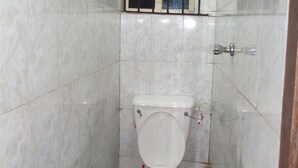 A small, tiled bathroom with a toilet, a visible pipe, and a wall-mounted faucet. - Solochus Hotel & Suites (Lagos)