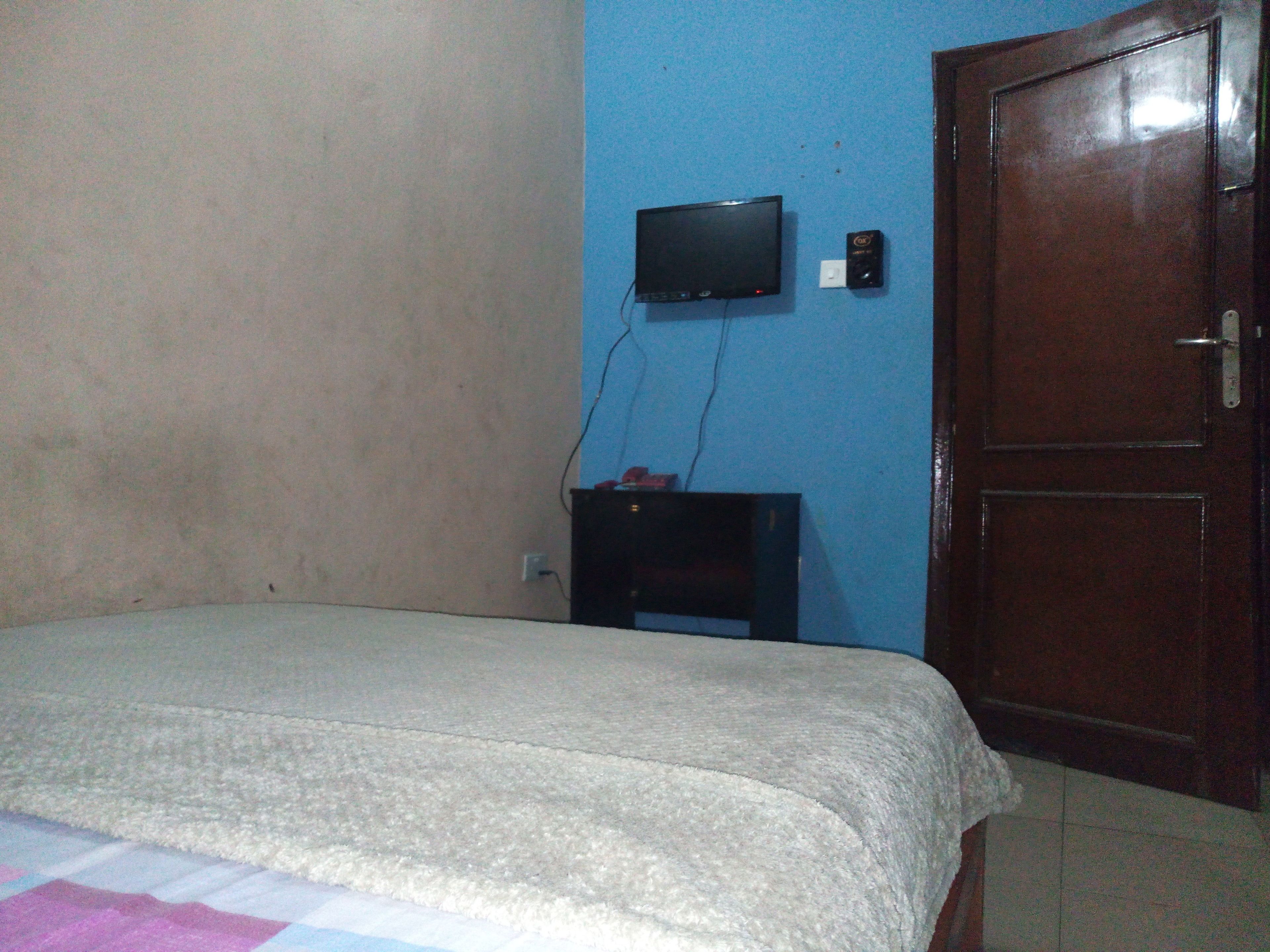 A room with a bed, a television mounted on the wall, and a door.