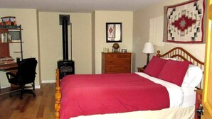 A bedroom with a wooden bed, a desk with books, a dresser, and a quilt on the wall. - Nederland Dual Level Apartment, Full Kitchen, No Cleaning Fee, Private! (Nederland)