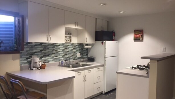 A modern kitchen with white cabinets, a tiled backsplash, and a gas stove. - Nederland Dual Level Apartment, Full Kitchen, No Cleaning Fee, Private! (Nederland)