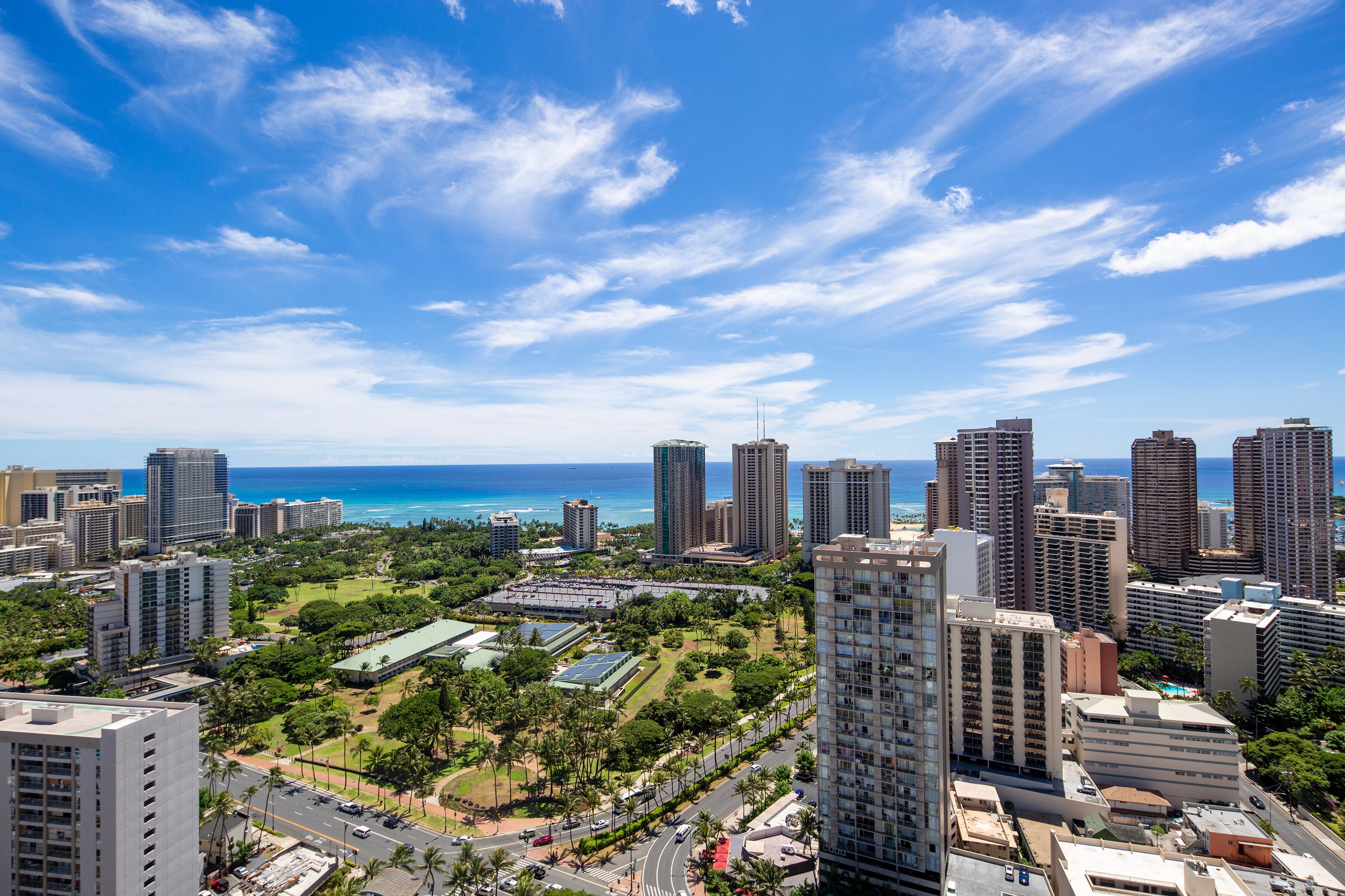 A cityscape with high-rise buildings, a clear blue sky, and a view of the ocean.
