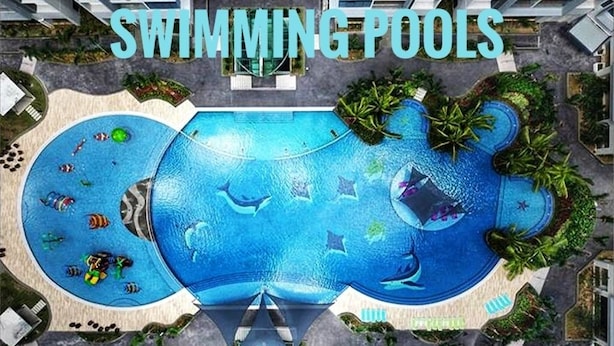 Een zwembadcomplex met verschillende zwembaden, waaronder een groot centraal bad en kleinere baden eromheen, omringd door palmbomen en terrasjes.