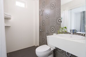 Une salle de bain avec des toilettes blanches, un lavabo avec un miroir et des carreaux décoratifs sur les murs.