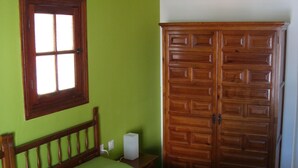 A room with a bed, a wooden wardrobe, and a window. - Hostal Durán (Álora)