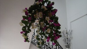A staircase with a wrought iron railing, a hanging floral arrangement, and a wall-mounted light fixture. - Hostal Durán (Álora)