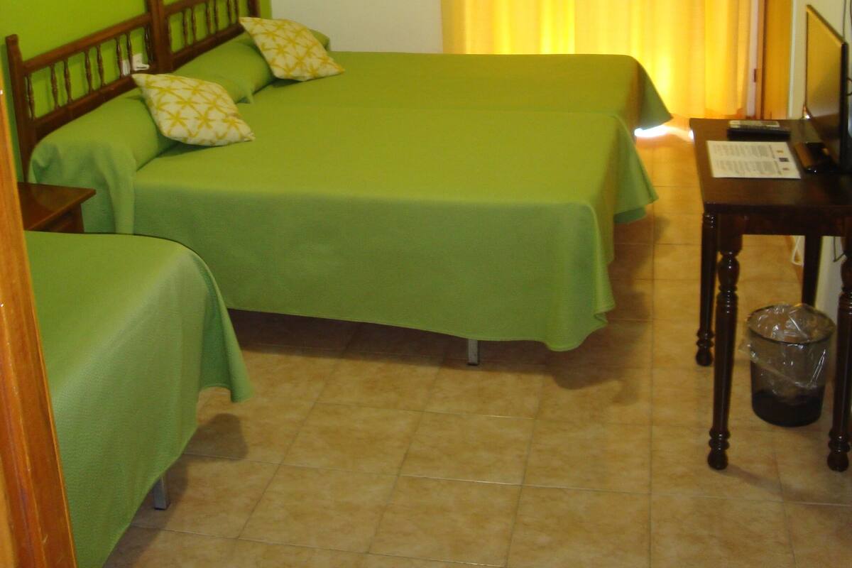 A room with two beds, a desk, and an air conditioning unit.