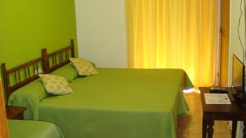 A room with two beds, a desk, and an air conditioning unit.