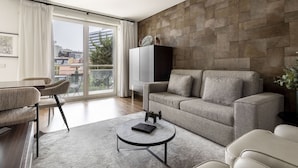 Una sala de estar moderna con un sofá gris, una mesa de centro redonda y un comedor con banco y sillas.