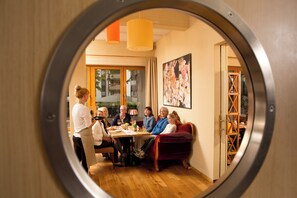 A dining area with a round table, wooden flooring, and a large painting on the wall.