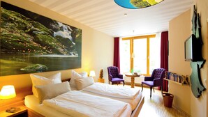 Une chambre d’hôtel avec deux lits, un grand tableau représentant une cascade, une télévision et une bibliothèque.