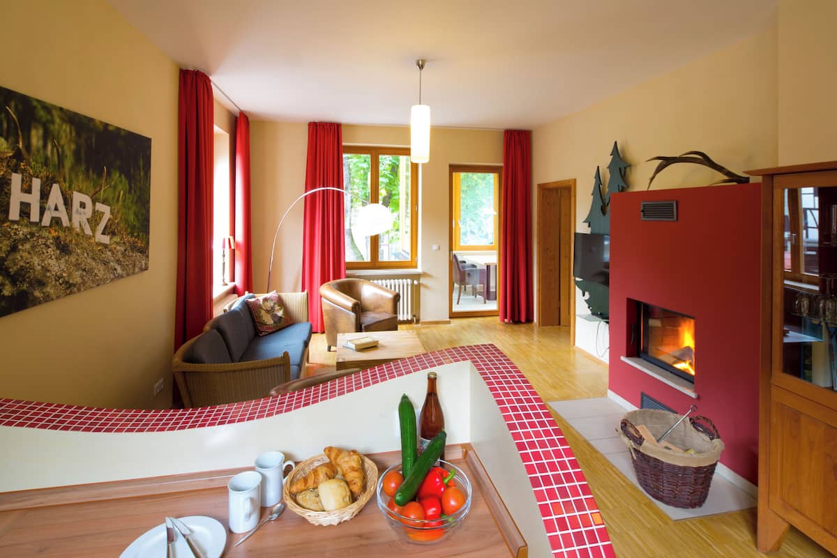 A cozy living room with a fireplace, a dining area with a table set for two, and a comfortable seating area with a sofa and armchairs.