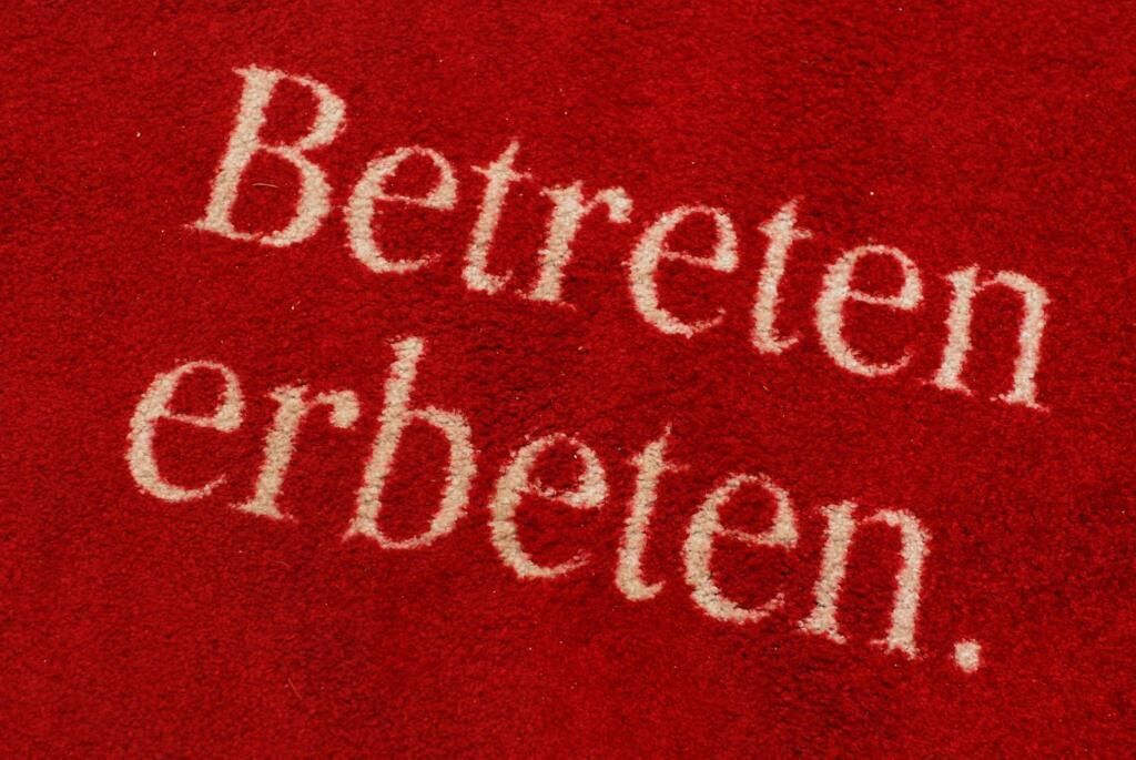 A red fabric with the words "Betreten erbeten."