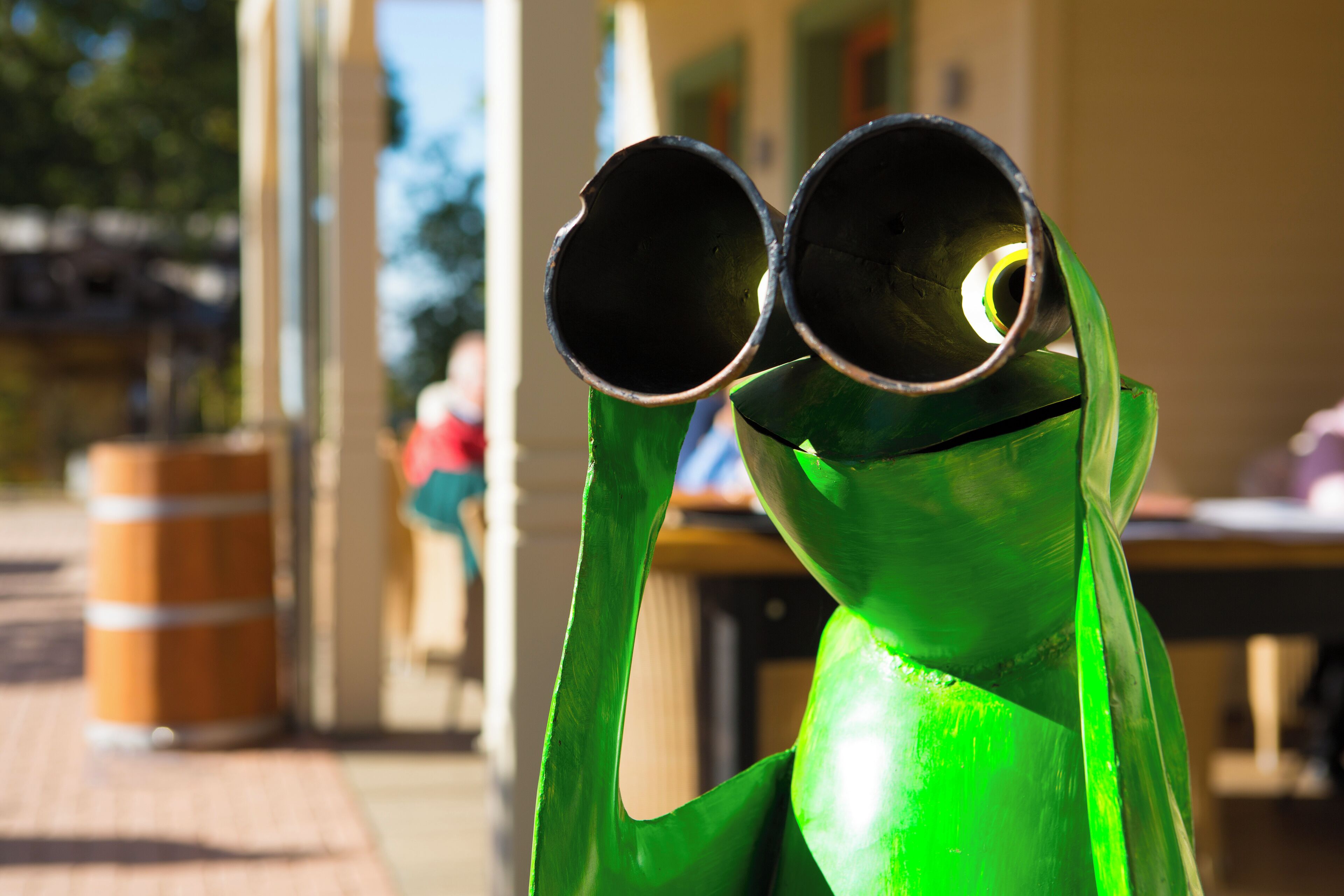 A green sculpture of a figure holding two cylindrical objects.